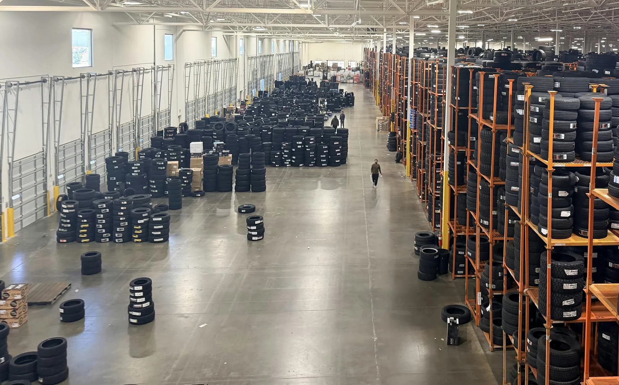 Overview of a USA Wheel & Tire warehouse floor with rows of tire racks and stacked tires