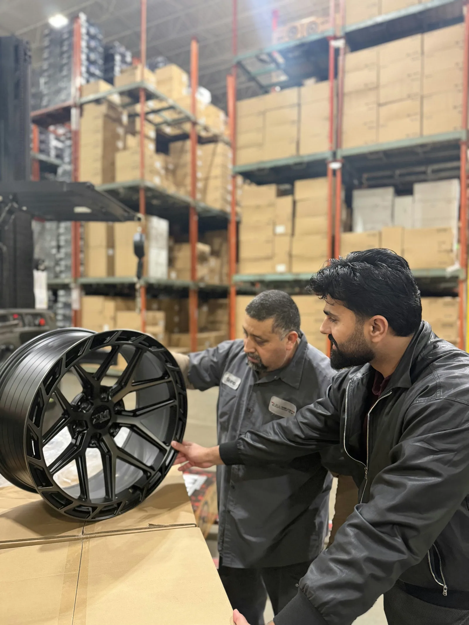 Two team members inspecting a black XM wheel in the warehouse